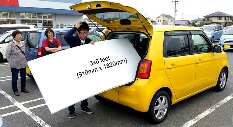 軽自動車に大きなスチレンボードが入らず困っている様子