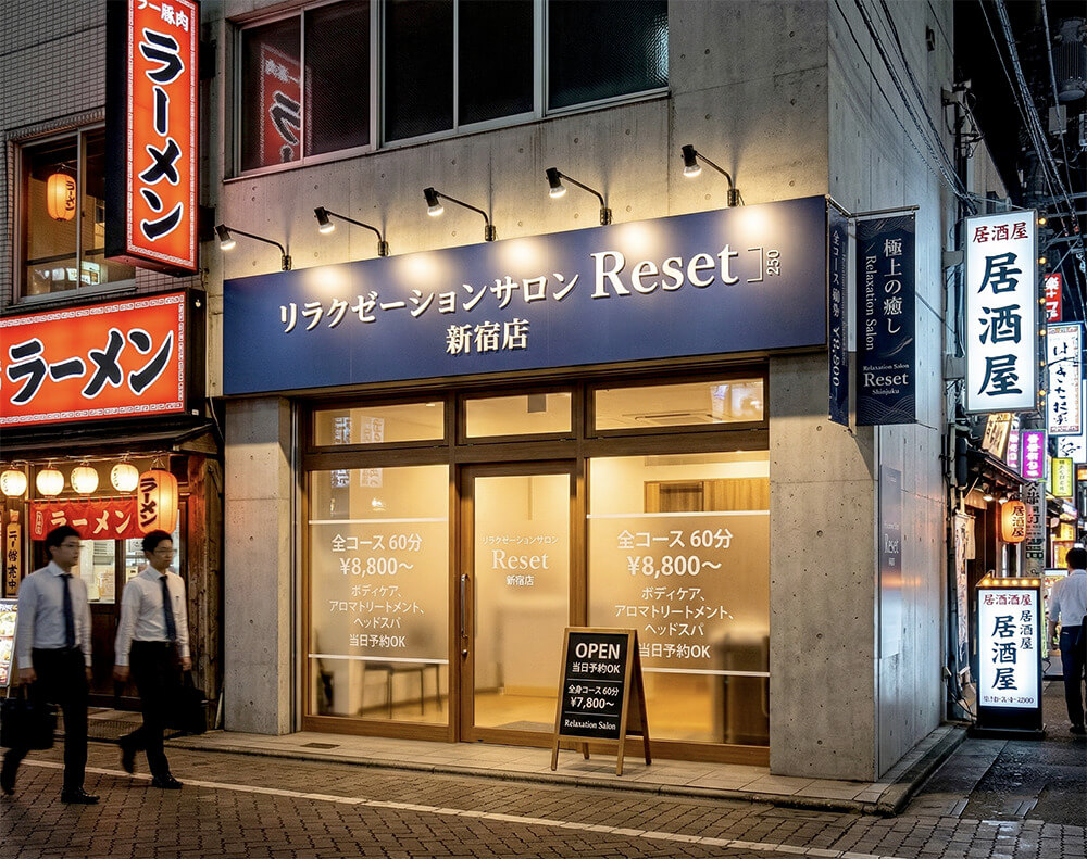 目立つ看板の施工事例。ネイビーのファサード看板と窓サインで都会的に目立たせたリラクゼーションサロンの完成外観